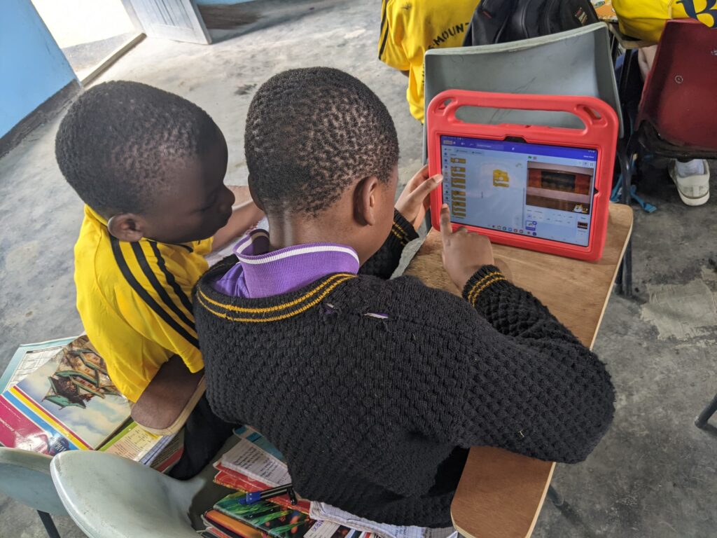 a group of boys sitting at a table looking at a tablet